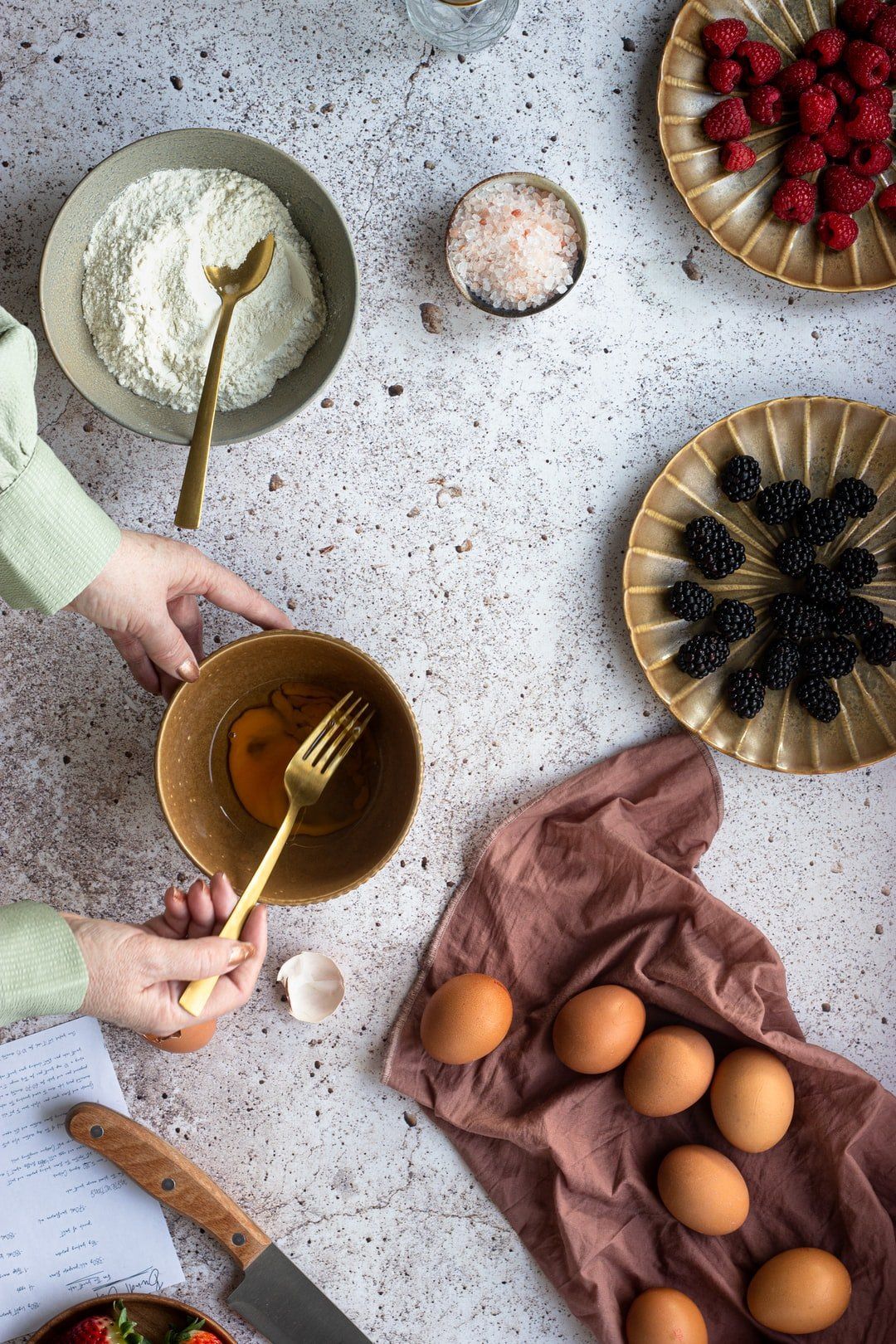 A person is cracking eggs into a bowl with a fork.
