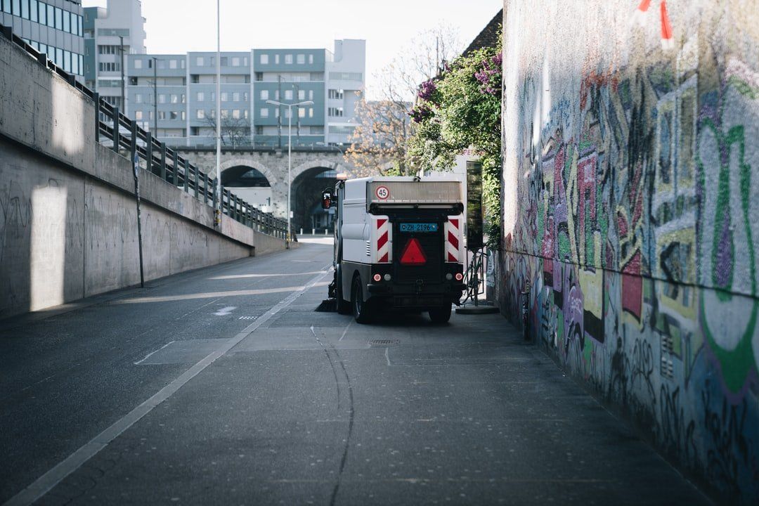 A truck is parked in an alleyway next to a graffiti covered wall.