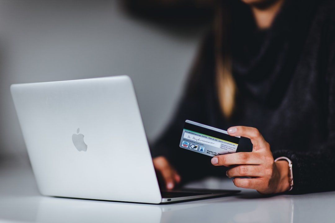 A woman shopping online holing a credit card in her left hand