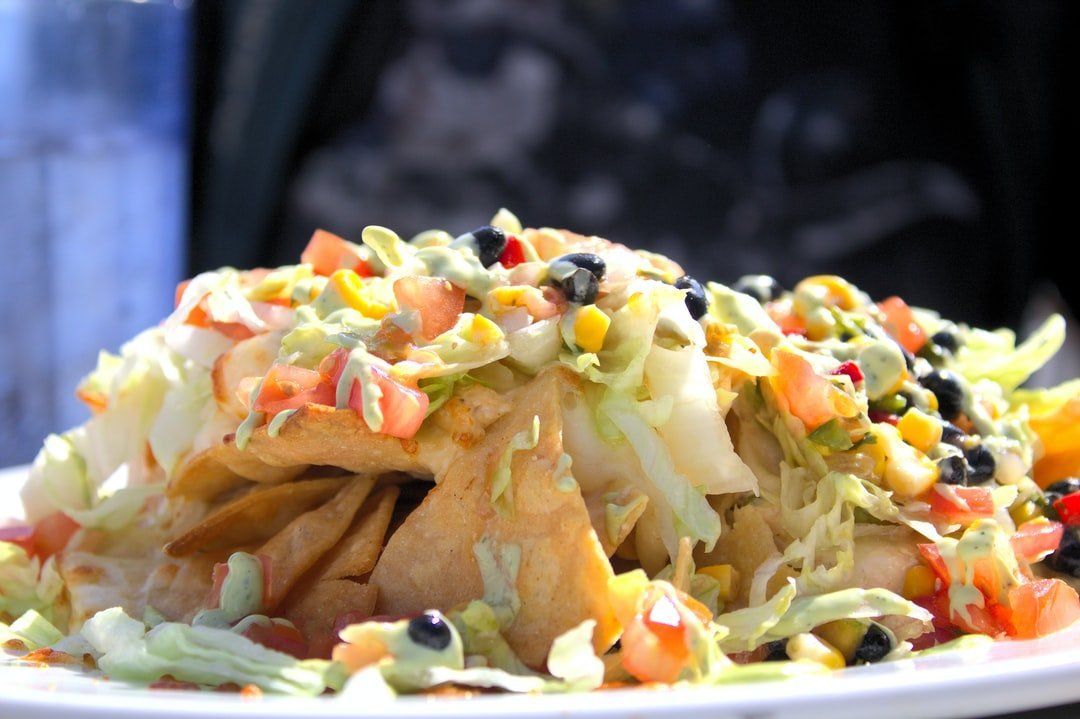 Nachos with lettuce, tomatoes, black beans, corn, and dressing.